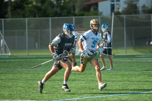 Newport Harbor’s #25 and Corona del Mar’s #5 sprinting off the field after faceoff.